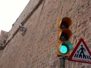 Un trabajador realiza trabajos de mejora en la muralla suspendido de la misma con un arnés