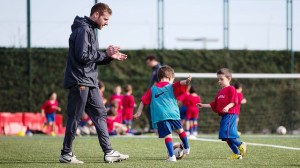 Un técnico del FCB Barcelona da ánimos a unos jóvenes jugadores durante el campus.