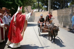 El obispo bendice a un 'minicarro' conducido por un niño y una niña y tirado por un pony.