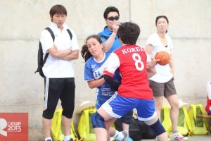 Una jugadora del Puchi alevín femenino intenta regatear a una jugadora de la selección de Korea.