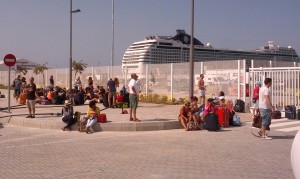 Los turistas esperan su barco sentados en el suelo y al sol