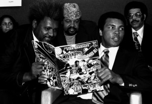 Muhammad Ali in person ojeando su propio cómic bajo la atenta mirada de Don King (izquierda).