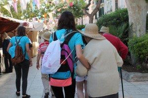 Una voluntaria lleva del brazo a una señora en el paseo de Vara de Rey