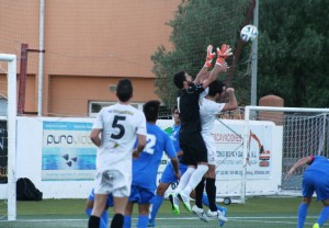 Fran Lozano, portero del Ferriolense, intenta atrapar el balón mientras que Pacheta le hace falta.