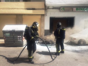 Dos bomberos durante la extinción del fuego que se originó en el contenedor de vídrio. 