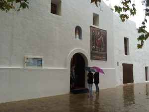 Dos vecinas con paraguas en las puertas de la iglesia.