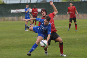 Cristian Cruz es derribado por el delantero Mateo Ferrer durante el partido de Son Bibiloni. Fotos: Fútbol Balear