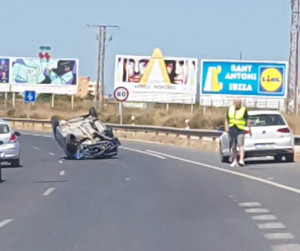 Imagen del coche volcado en la carretera de aeropuerto. 