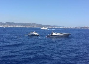 Imagen del yate que ha comenzado a hundirse en es Freus por una vía de agua, y de los navegantes en el mar, a punto de ser rescatados. 