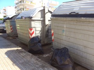 Contenedores llenos de basura y sucios alrededor. 